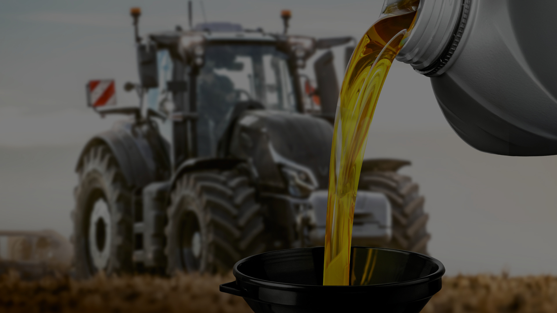 Lubricant being poured into a funnel with a Valtra tractor in the background